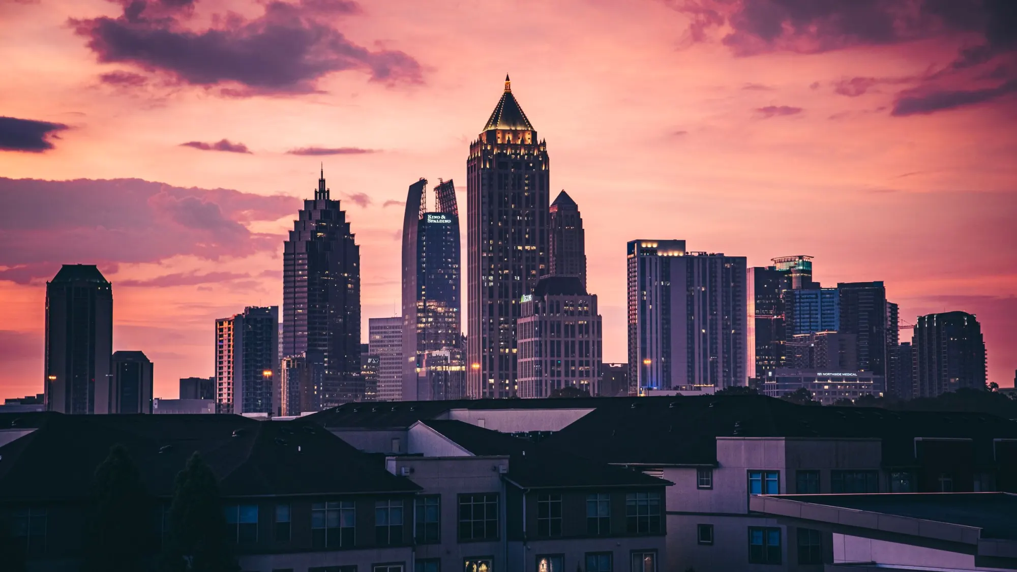 City towers against a pink sunset sky.